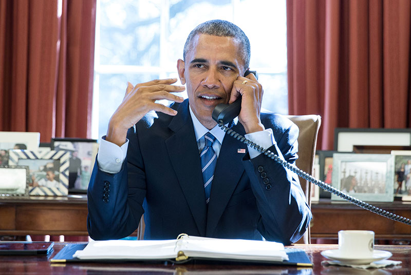 President Barack Obama talks on the phone with pastors who offer a birthday prayer during a call in the Oval Office, Aug. 4, 2015. (Official White House Photo by Pete Souza)