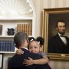President Barack Obama greets National Security Staff (NSS) for departure photos in the Oval Office, February 1, 2012. Arianna Holmes, age 3, hugs President Obama before taking a departure photo with her family in the Oval Office of the White House. 
